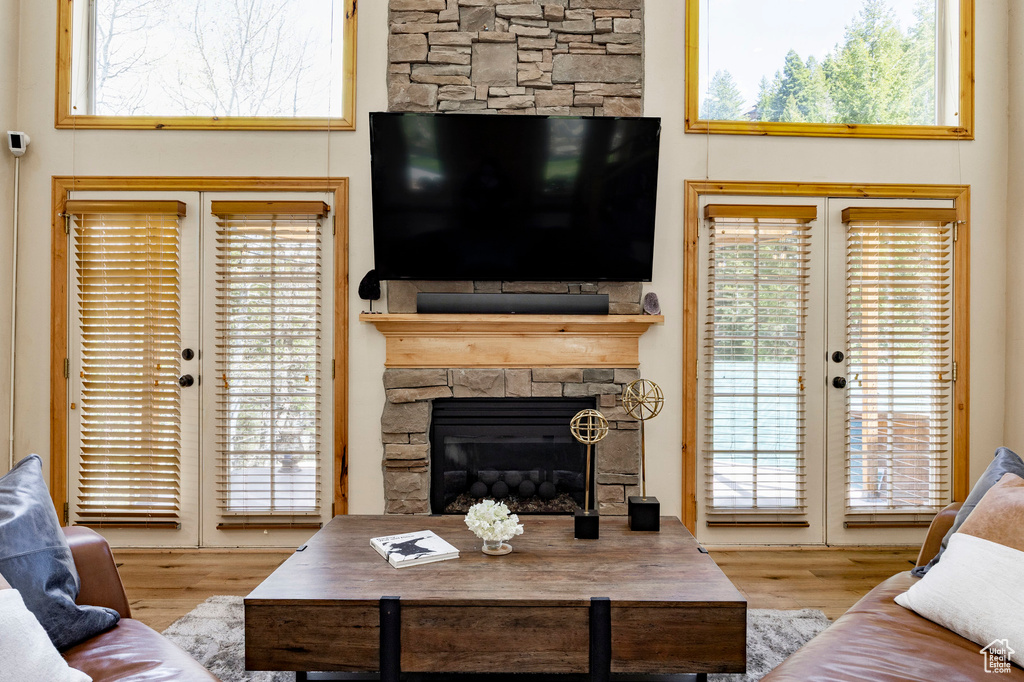Living area featuring wood finished floors, a stone fireplace, and french doors