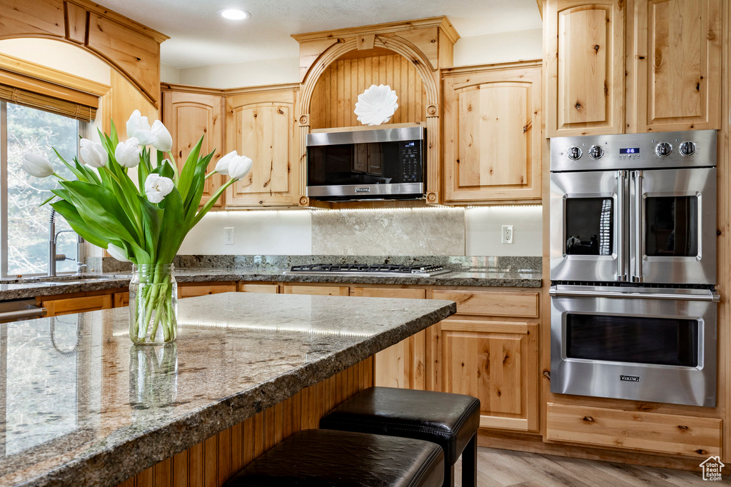 Kitchen with stainless steel appliances, a sink, light brown cabinets, light wood-type flooring, and recessed lighting
