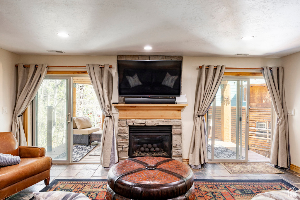 Living room featuring plenty of natural light, recessed lighting, a fireplace, stone tile flooring, and a textured ceiling