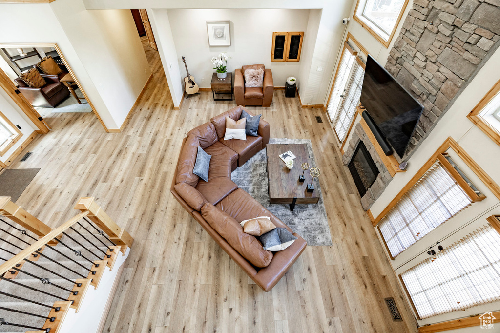 Living area featuring a glass covered fireplace, healthy amount of natural light, wood finished floors, baseboards, and a towering ceiling