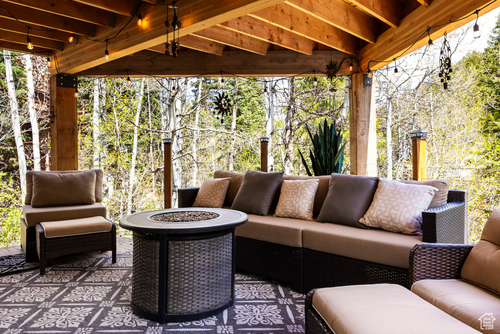 View of patio with an outdoor living space with a fire pit and view of wooded area