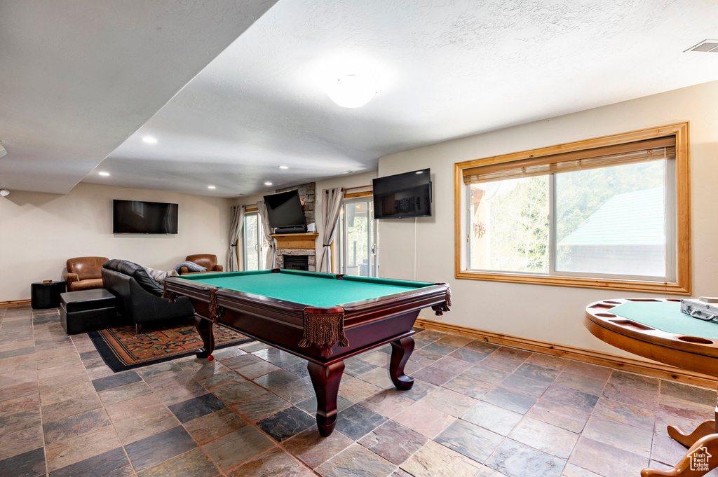 Playroom featuring baseboards, recessed lighting, a stone fireplace, stone finish flooring, and billiards