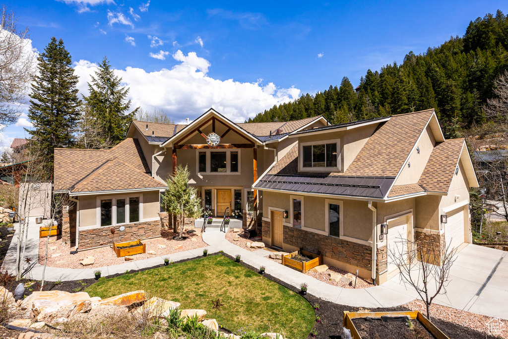 Craftsman-style house featuring stucco siding, stone siding, driveway, and an attached garage
