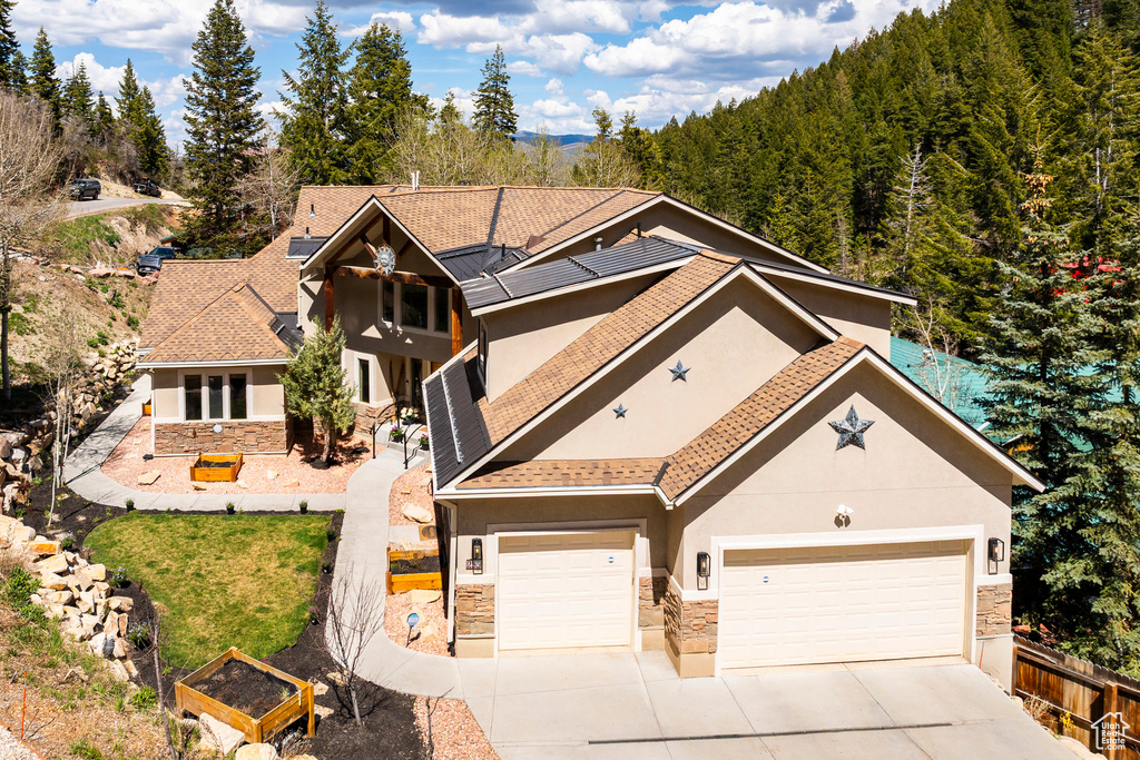 View of front of home with stone siding, stucco siding, driveway, and an attached garage