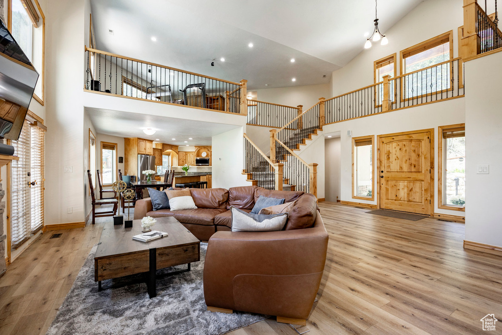 Living room with a towering ceiling, stairs, light wood-style flooring, baseboards, and recessed lighting