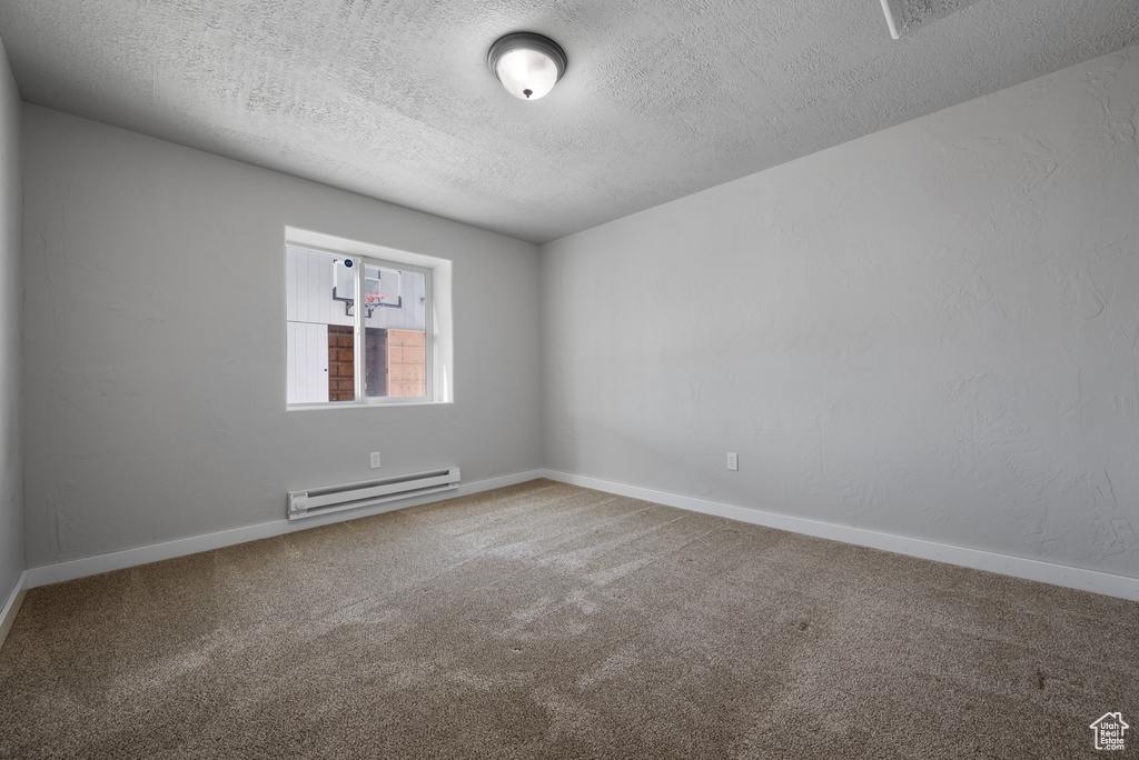 Spare room with a baseboard radiator, a textured ceiling, carpet, and baseboards