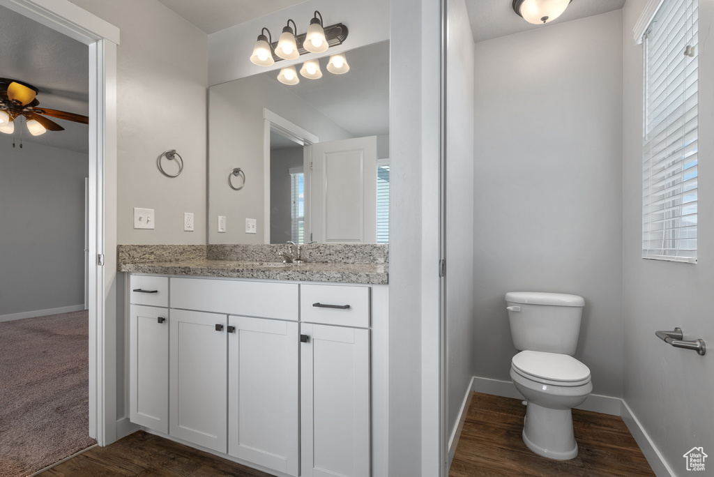 Bathroom with vanity, toilet, ceiling fan, and wood finished floors