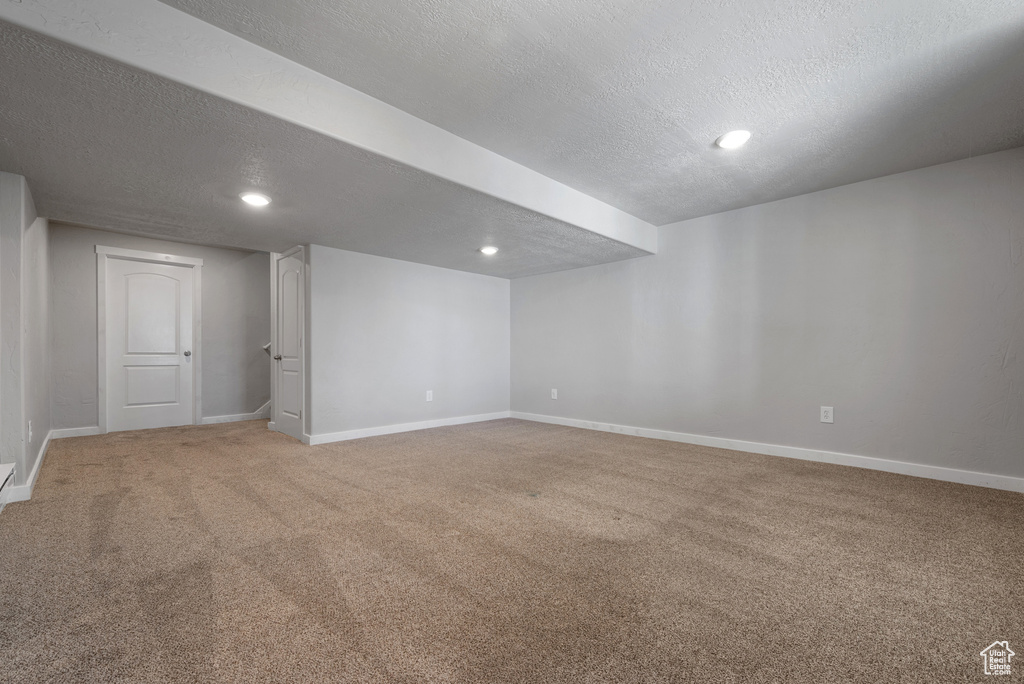 Finished basement with a textured ceiling, light carpet, baseboards, and recessed lighting