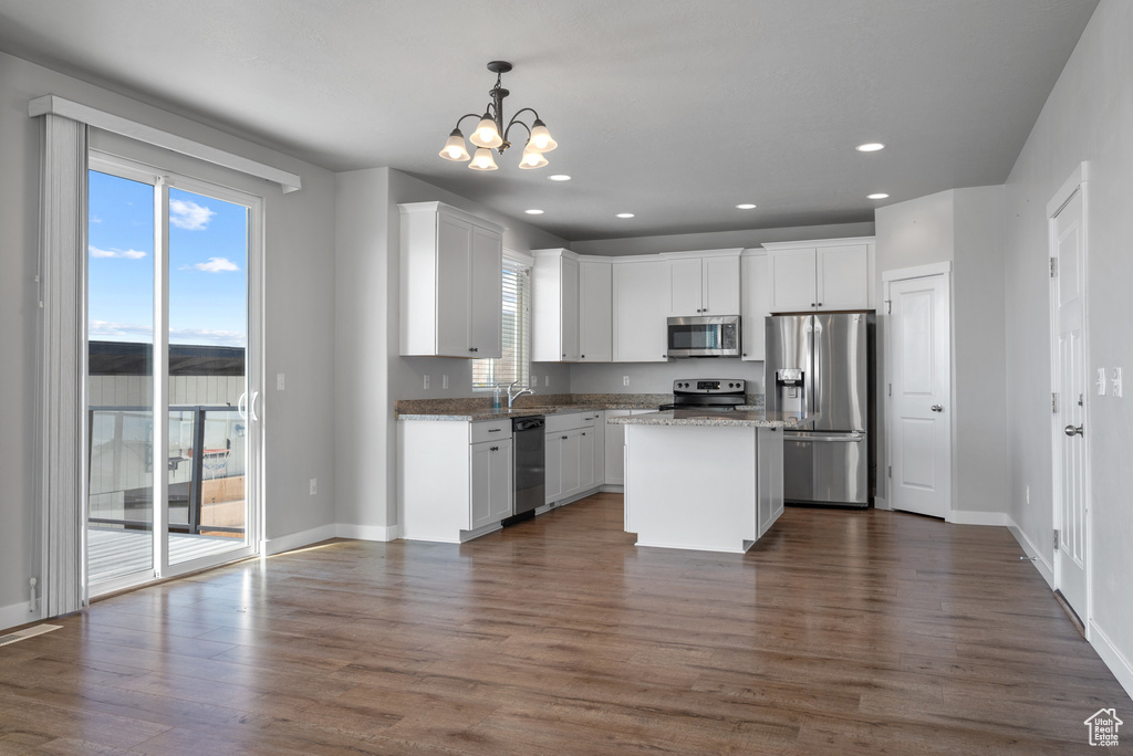 Kitchen with stainless steel appliances, a chandelier, white cabinets, baseboards, and recessed lighting