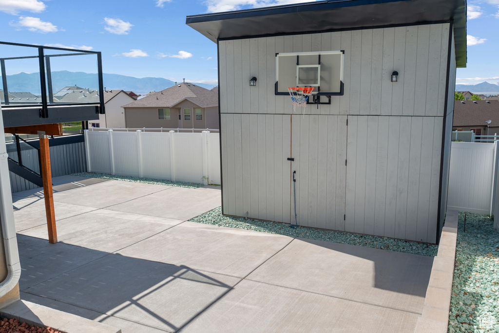 View of basketball court with a mountain view, a fenced backyard, and plenty of natural light