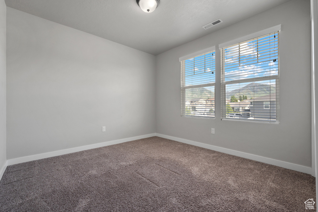 Carpeted spare room featuring baseboards