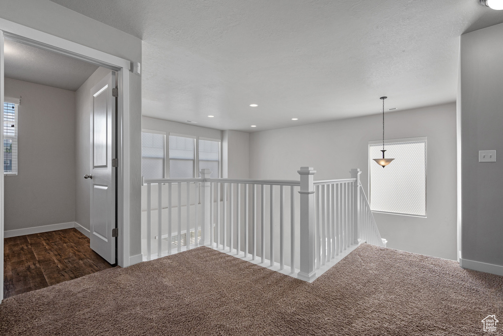 Hall featuring dark carpet, baseboards, an upstairs landing, and recessed lighting
