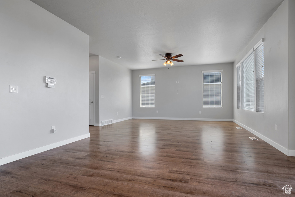 Unfurnished room featuring a ceiling fan, baseboards, and dark wood-type flooring