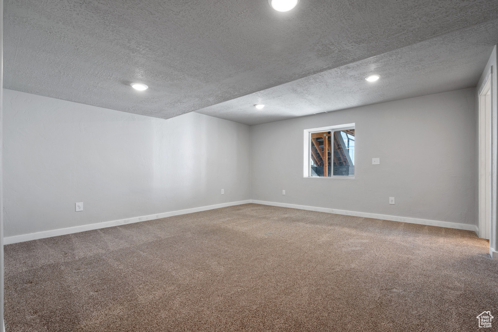 Carpeted empty room with a textured ceiling, baseboards, and recessed lighting