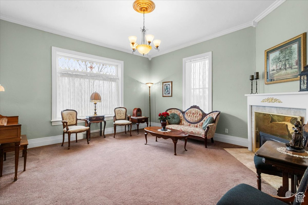 Sitting room featuring a notable chandelier, ornamental molding, light carpet, and a premium fireplace