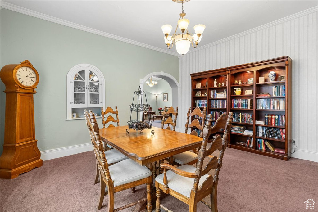 Carpeted dining space featuring crown molding and a notable chandelier