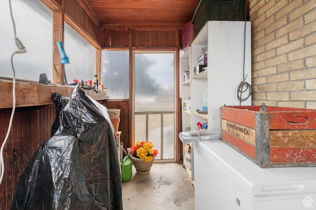 Laundry room with wooden ceiling and brick wall