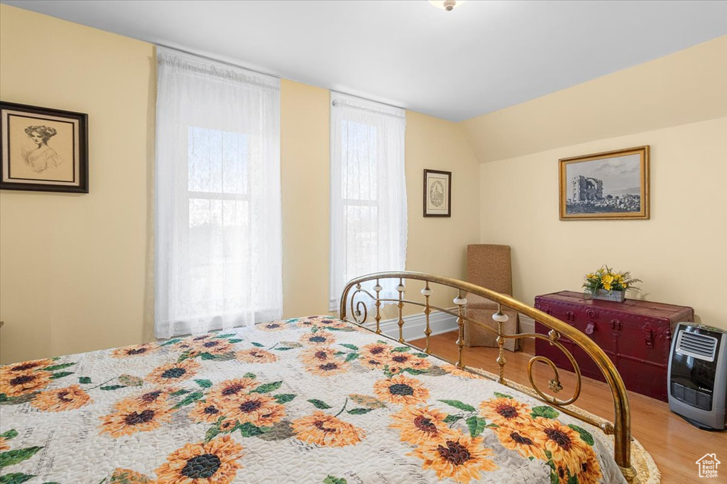 Bedroom with hardwood / wood-style floors, lofted ceiling, and heating unit