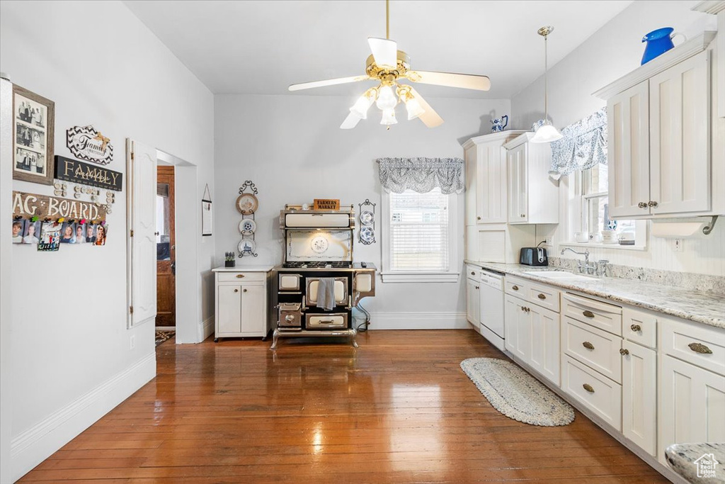 Kitchen featuring light stone countertops, sink, dishwasher, dark hardwood / wood-style floors, and white cabinetry