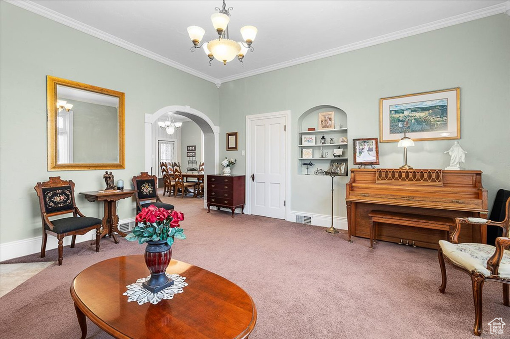 Sitting room with carpet, built in features, ornamental molding, and a chandelier