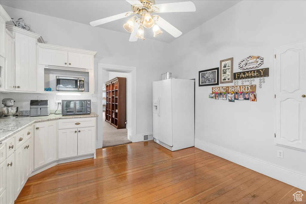 Kitchen with white cabinets, ceiling fan, white refrigerator with ice dispenser, and light hardwood / wood-style flooring