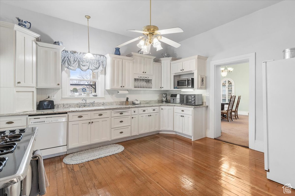 Kitchen featuring white appliances, ceiling fan with notable chandelier, sink, light hardwood / wood-style flooring, and white cabinetry