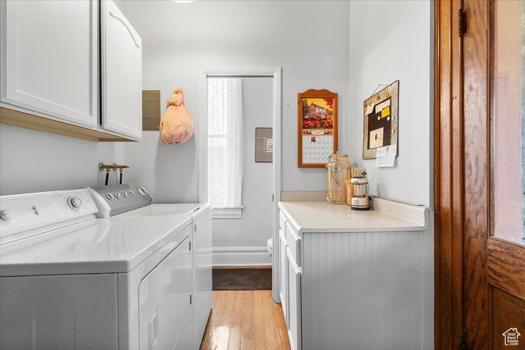 Clothes washing area featuring light hardwood / wood-style flooring, cabinets, and independent washer and dryer