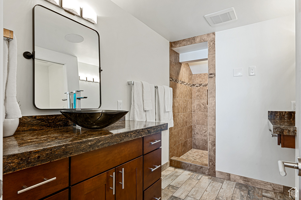 Bathroom with a walk in shower, wood finished floors, vanity, and visible vents