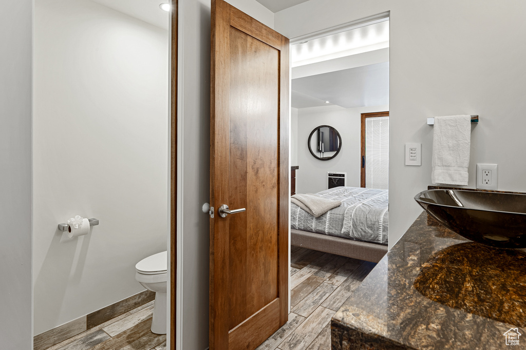 Ensuite bathroom with a sink, wood finished floors, toilet, and connected bathroom