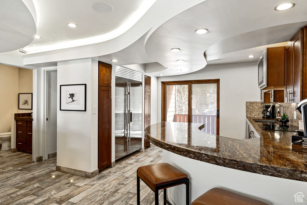 Kitchen with built in refrigerator, light wood-type flooring, a peninsula, and recessed lighting
