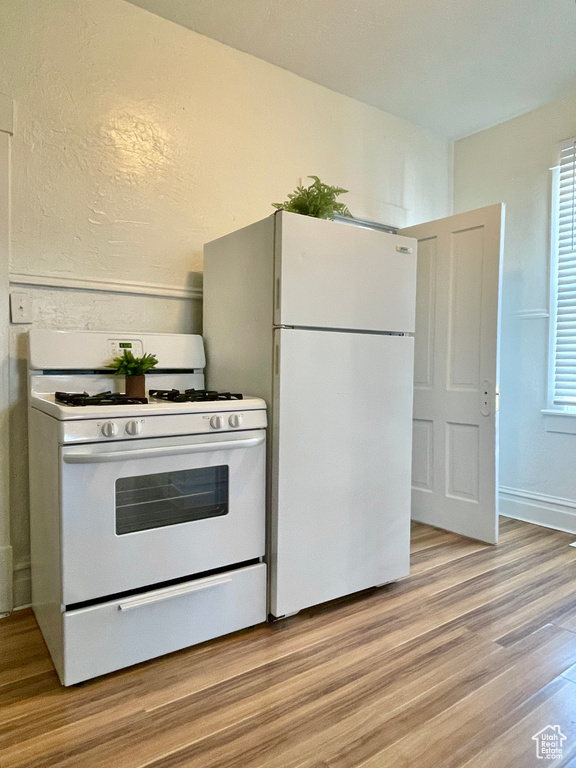 Kitchen with light wood-type flooring and white appliances