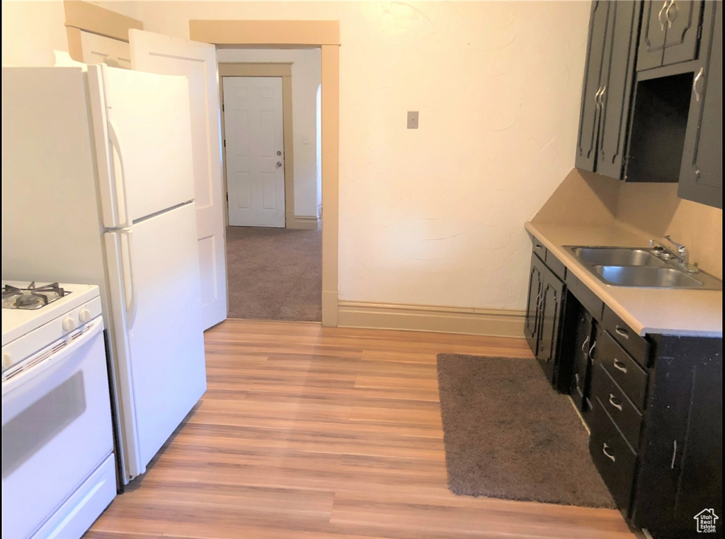 Kitchen with white stove, light hardwood / wood-style floors, and sink