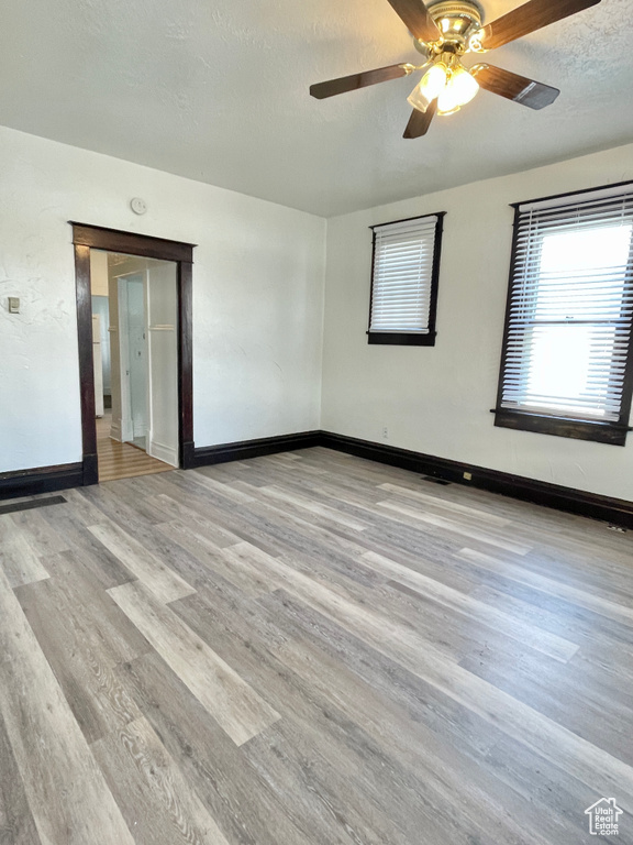 Unfurnished room with a textured ceiling, light wood-type flooring, and ceiling fan