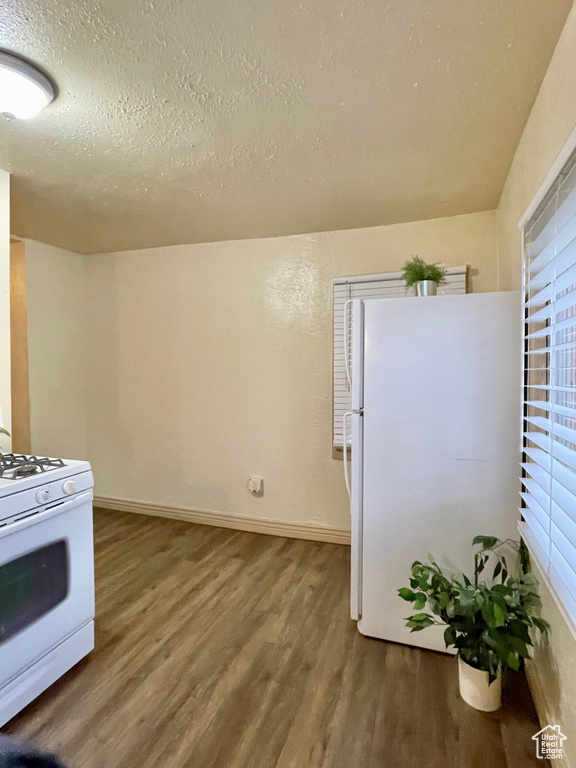 Kitchen with a textured ceiling, hardwood / wood-style floors, and white appliances