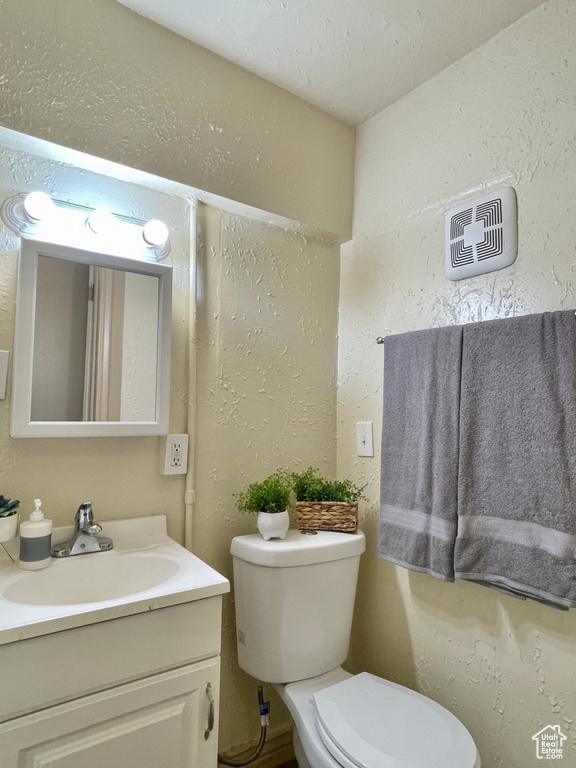 Bathroom with vanity, a textured ceiling, and toilet