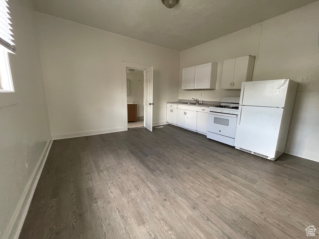 Kitchen featuring sink, white cabinets, dark wood-type flooring, and white appliances