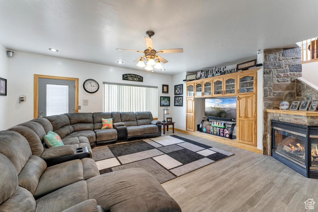 Living room featuring ceiling fan, a fireplace, and light hardwood / wood-style flooring
