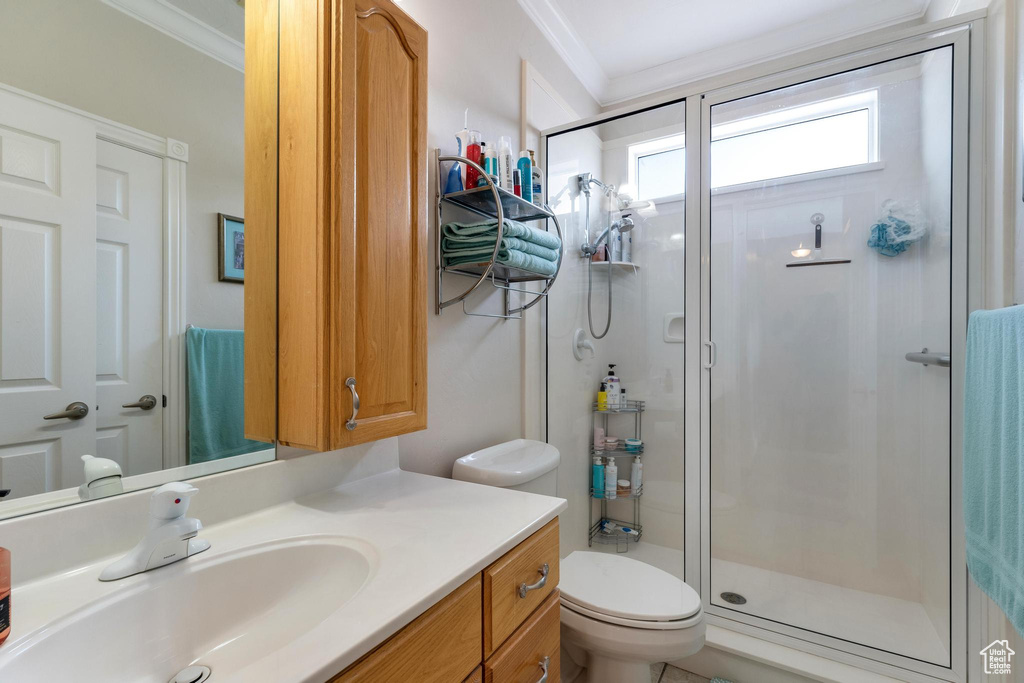 Bathroom featuring toilet, a shower with door, vanity, and ornamental molding