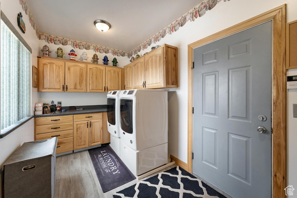Washroom featuring washing machine and clothes dryer, a wealth of natural light, cabinets, and dark hardwood / wood-style floors