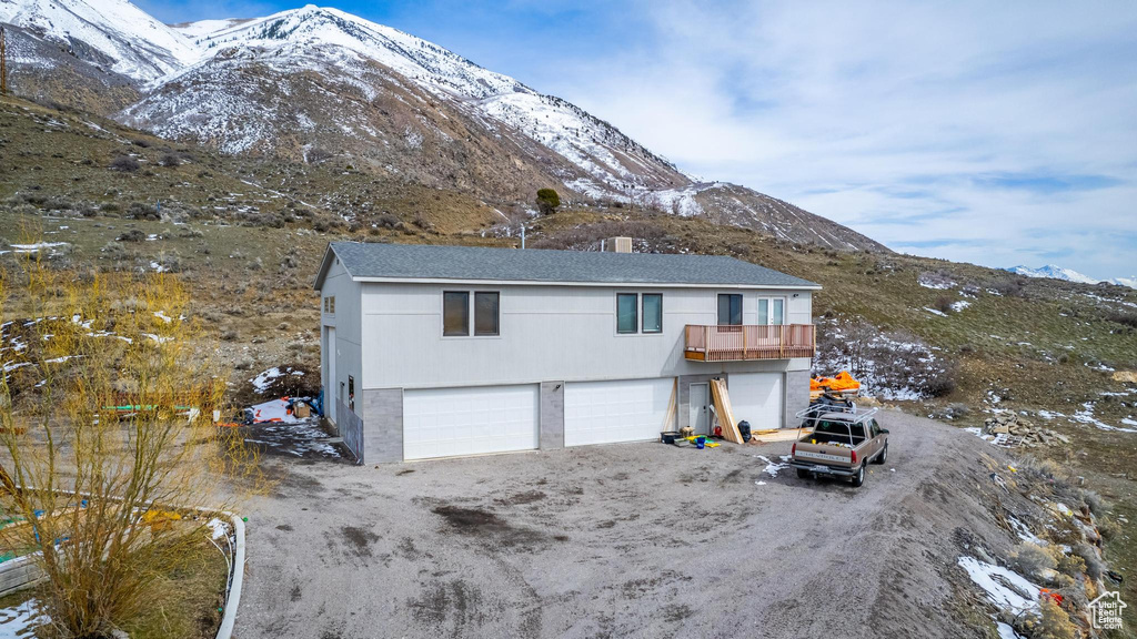 View of front of home with a mountain view, a garage, and a balcony