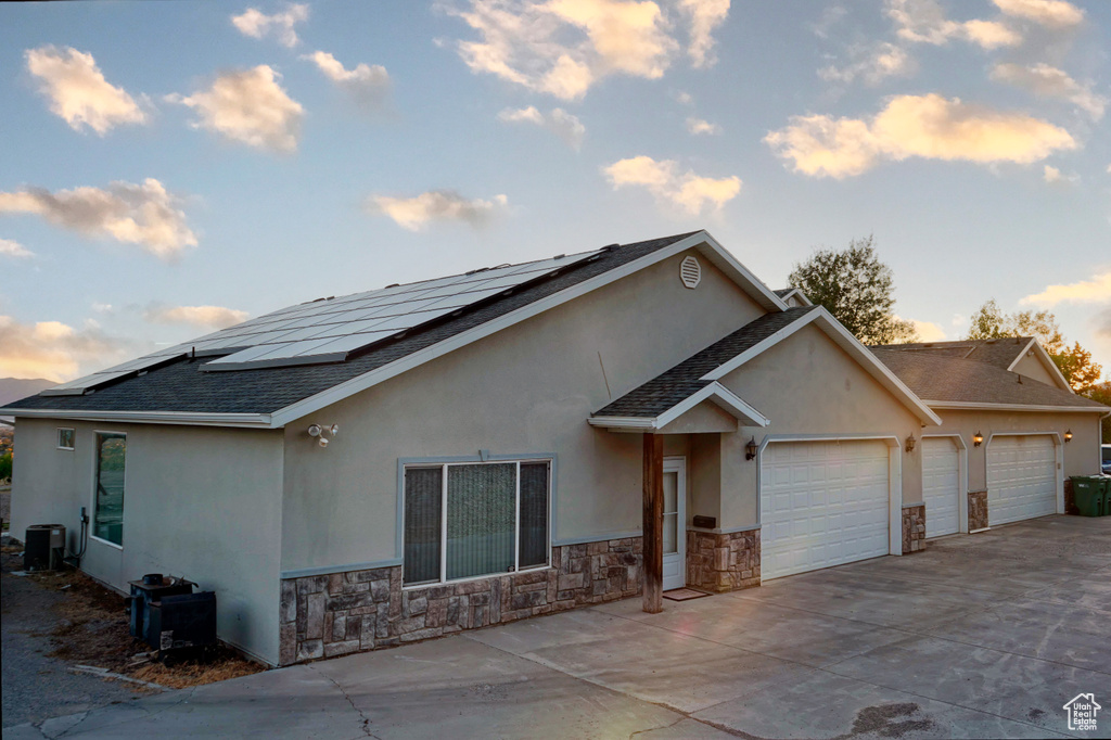 View of front of house featuring solar panels, a garage, and central AC