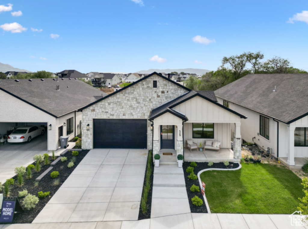 Modern farmhouse featuring a carport, a mountain view, a front yard, a porch, and a garage