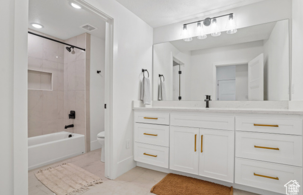 Full bathroom featuring vanity, tile patterned flooring, tiled shower / bath combo, and toilet