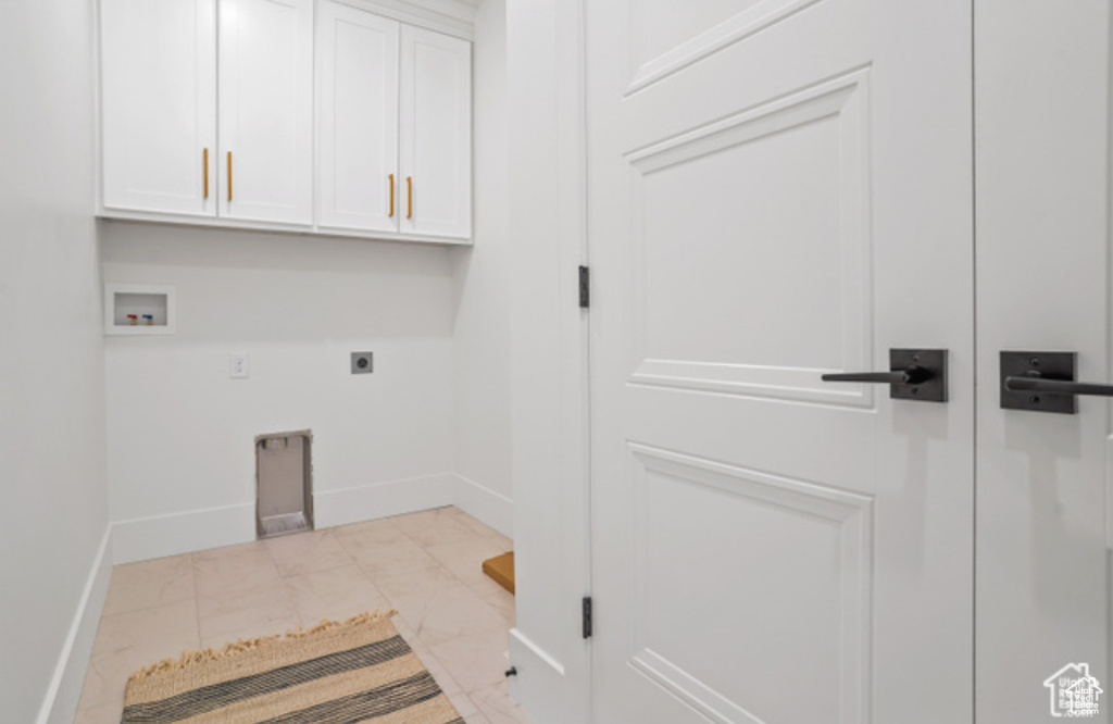Washroom featuring electric dryer hookup, washer hookup, light tile patterned floors, and cabinets