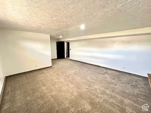 Carpeted spare room with a textured ceiling and baseboards