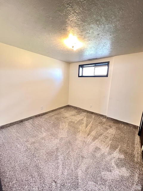 Unfurnished room with a textured ceiling, carpet, and baseboards