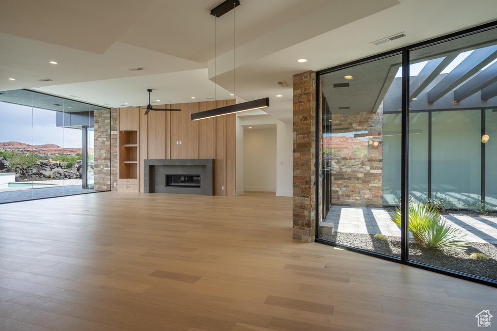 Unfurnished living room with floor to ceiling windows, ceiling fan, a mountain view, and light hardwood / wood-style floors