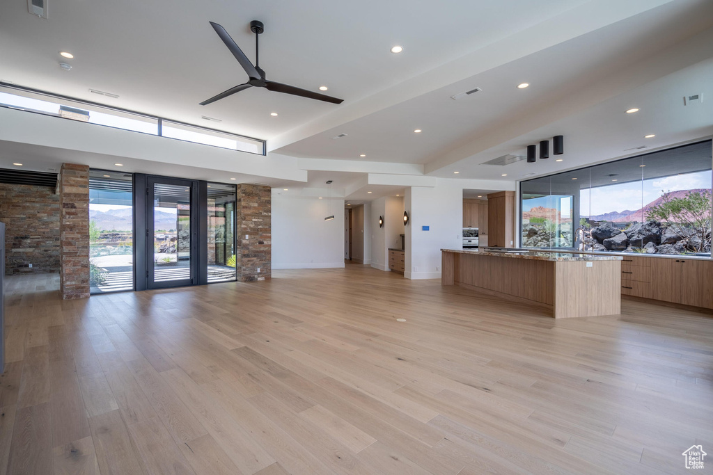 Kitchen with light stone counters, plenty of natural light, a large island, and light wood-type flooring