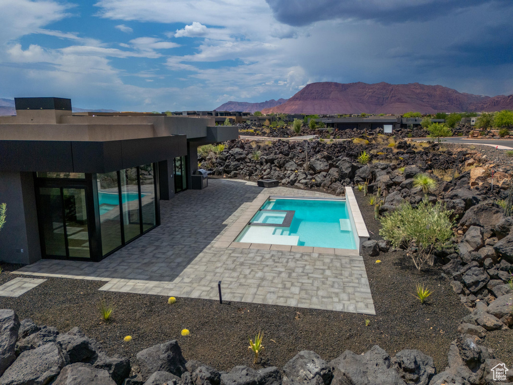 View of swimming pool featuring a mountain view, a patio, and an in ground hot tub