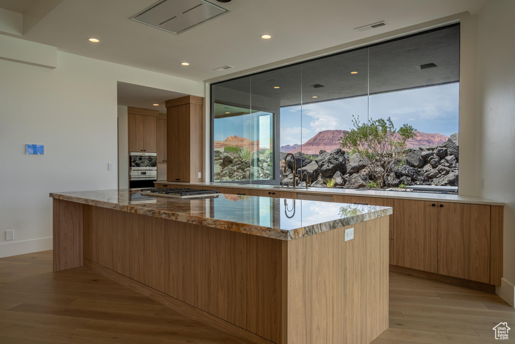 Kitchen featuring light stone countertops, a center island, sink, and stainless steel gas cooktop